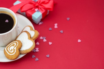 Love, Valentine's Day. Cup of coffee and heart shaped cookies, biscuits. Top view. Red background with gift boxes. Copy space.