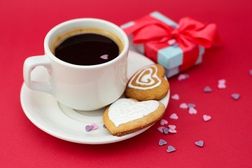 Love, Valentine's Day. Cup of coffee and heart shaped cookies, biscuits. Top view. Red background with gift boxes.
