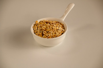 Dry oatmeal in a bowl isolated on white background. View from above