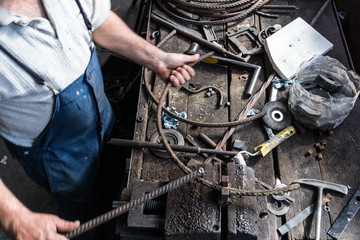 Blacksmith making wrought Iron with industrial bender equipment machine for metal bending.
