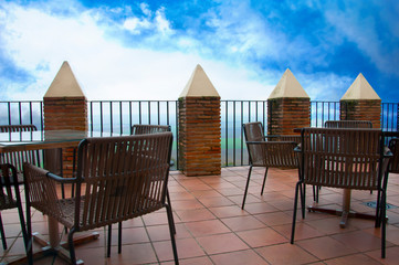Wooden tables and chairs on the large terrace, blue sky
