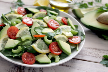 Fresh salad with spinach, avocado, tomato and lemon. Top view with copy space. Vegetarian and vegan food.
