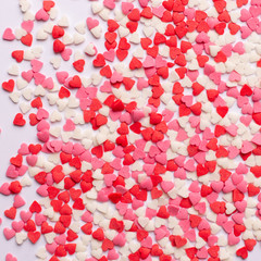 Red, pink and white heart shaped sweets scattered on white background. space for text. flat lay.