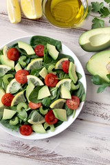 Fresh salad with spinach, avocado, tomato and lemon. Diet food. Top view with copy space. Vegetarian and vegan gosh.