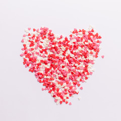 Fototapeta na wymiar Red, pink and white heart shaped sweets in the shape of a heart scattered on white background. space for text. flat lay. valentine concept