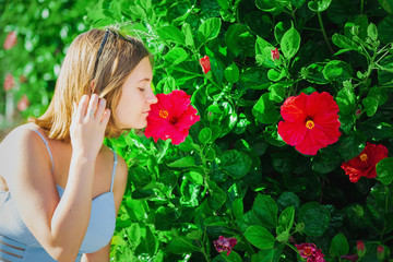 Obraz na płótnie Canvas young girl sniffs red flower
