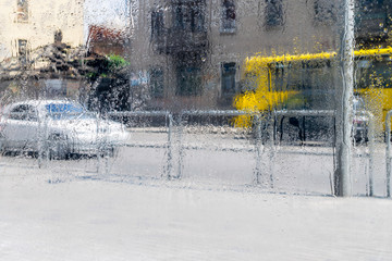 Rain drops in the window of a busy street. Urban transport rides in rainy weather. Abstract background
