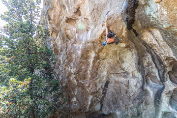 Fototapeta premium The last movements to reach the summit by a male climber. Rock climbing inside the Andes mountains at Cajon del Maipo, Chile. Climber solving the movements of 