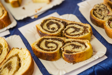 Delicious strudel piece with spiral inside on white cardboard plate on blue table
