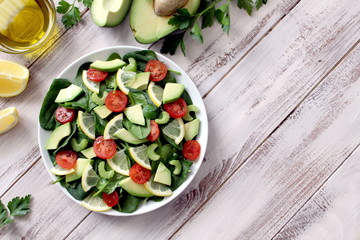 Fresh salad with spinach, avocado, tomato and lemon. Diet food. Top view with copy space. Vegetarian and vegan gosh.