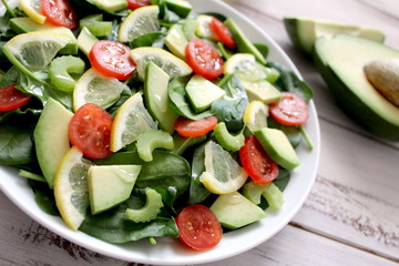 Fresh salad with spinach, avocado, tomato and lemon. Diet food. Top view with copy space. Vegetarian and vegan gosh.