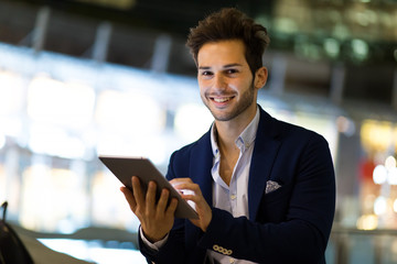Fototapeta premium Young manager using a digital tablet outdoor in a modern city at night