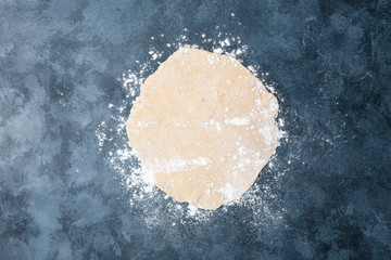 Female hands rolling dough on a table with a wooden rolling pin. Top view. Flat lay.