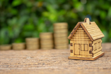 real estate concept image of house model with stack of coins and space for text.