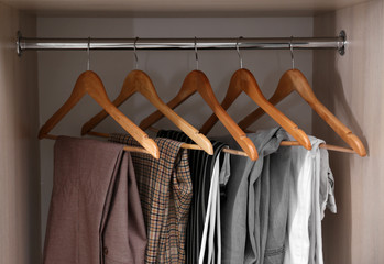 Collection of stylish pants on hangers in wardrobe closet