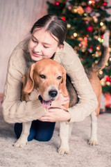 girl hugging her dog in front of a christmas tree