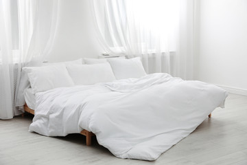 Comfortable bed in light room. Interior design - obrazy, fototapety, plakaty