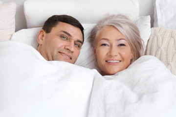 Mature couple under blanket in comfortable bed