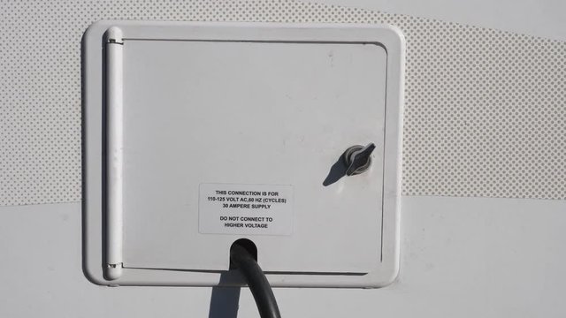 Door containing electrical connection cord on side of RV vehicle.