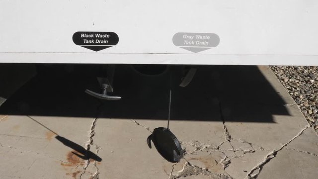 Black Waste and Gray Waste Tank Drain location on side of RV vehicle.