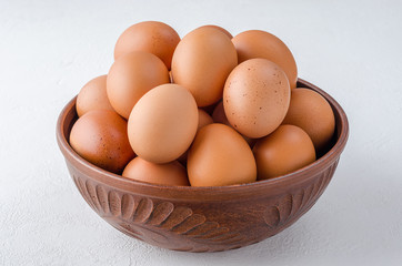 Red chicken eggs in a clay bowl.