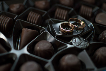 Wedding rings lie on the chocolate box