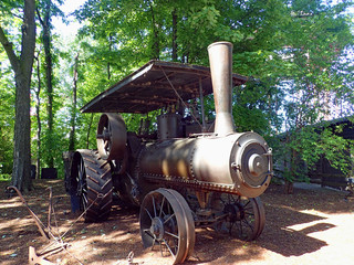 An old copper colored turn of the 19th century steam engine agricultural ploughing tractor with...