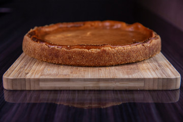 The round fresh backed cheesecake on wooden board. 