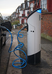 Fototapeta na wymiar An electric vehicle being charged at a charging station at a residential street in London, UK in the evening.
