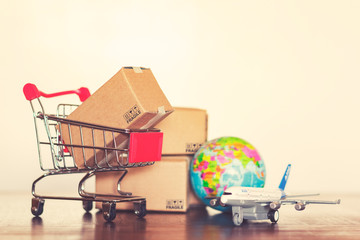 Shopping cart with cartons, airplane and earth globe. Vintage effect