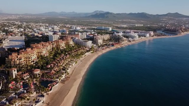 Aerial view of Medano Beach in Cabo San Lucas. Hotels at the front and the city behind. Shot at first hours in the morning. Baja California Sur, Mexico.