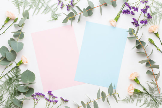 Fototapeta Flowers composition. Paper blank, carnation flowers, eucalyptus branches on pastel  background. Flat lay, top view, copy spaceFlat lay stiil life.