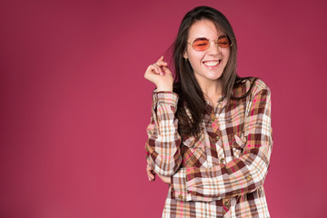 Long haired young brunette stylish girl smiling and laughing on pink background