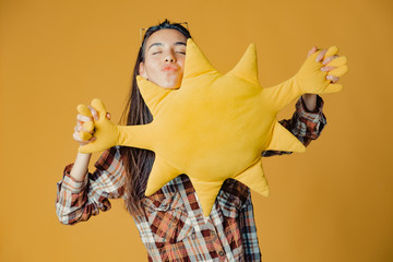 Young caucasian brunette girl with toy sun on orange background