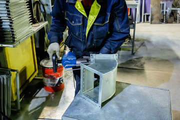 Fototapeta premium Worker in metalworking plant installing a rivets into part for construction ducts of industrial air condition system by using pneumatic riveter