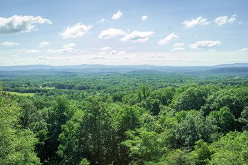 Fototapeta na wymiar Aerial Photo of a Forest in the Countryside - with a Long Stretch of Green Trees, Patches of Farmland and Mountains in the Distance on a Bright, Summer Day in the Appalachian United States