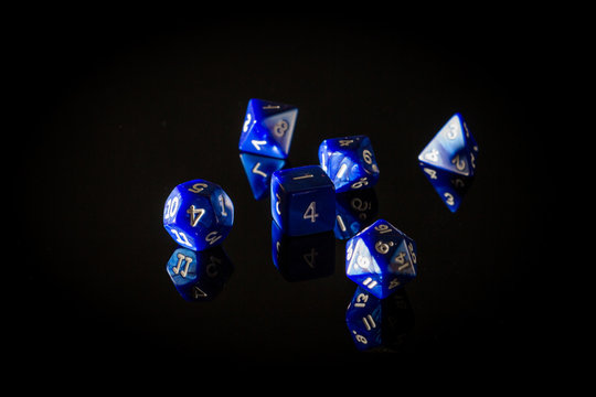 Moody, Shadowy Photo of Six Blue Role Playing Gaming Dice Displayed on a Reflective Surface, with a Dark Black Background