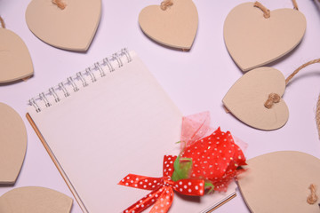 Red rose on  Blank notepad for copy space and Wooden hearts shape  on white blackground . Valentines Day background.  .  wedding day