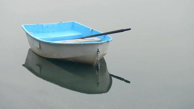 Dinghy rowboat at anchor in a quiet foggy cove with no horizon line visible. Great background for graphics or title page. Isolated.