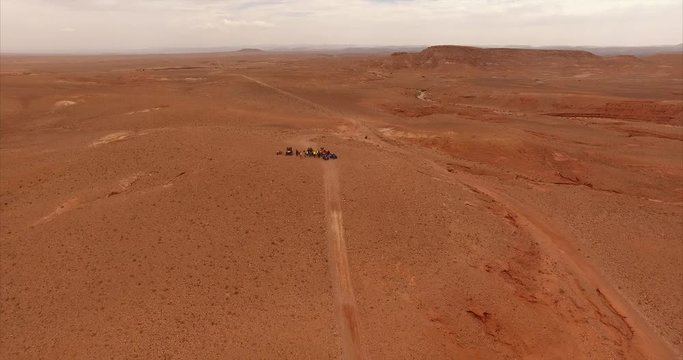 Aerial shot moving away from a group of quads in the middle of desert (Morocco)