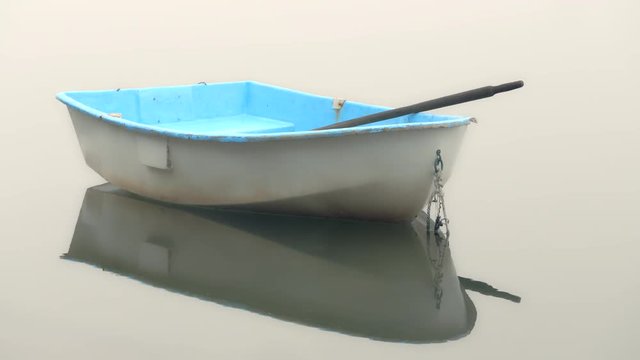 Dinghy rowboat at anchor in a quiet foggy cove with no horizon line visible. Great background for graphics or title page. Isolated.