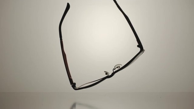 SLOW MOTION: Eyeglasses fall down to the the white surface