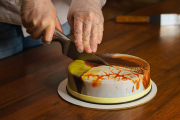 Confectioner cuts dacquoise cake in mirrored glaze. Home cooking. Modern cooking