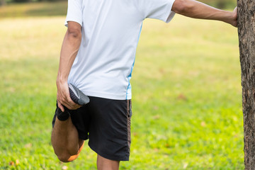 Young athlete man streching in the park outdoor. male runner warm up ready for jogging on the road outside. asian Fitness walking and exercise on footpath in morning. wellness and sport concepts