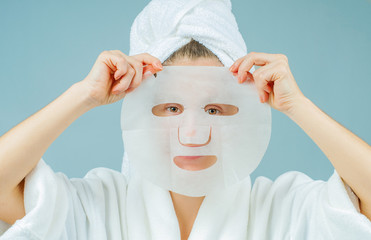 Facial care and beauty treatments. Beautiful woman with a sheet moisturizing mask on her face.