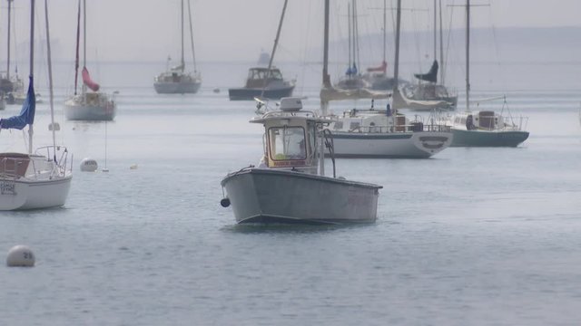 ROCKPORT, MAINE circa SEPT. 2018 - Harbor master boat slowly patrols past sailboats at anchor in slow motion