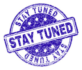 STAY TUNED stamp seal watermark with distress texture. Designed with rounded rectangles and circles. Blue vector rubber print of STAY TUNED tag with retro texture.