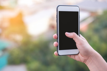 hand holding smartphone or mobile phone with city building background and copy space.
