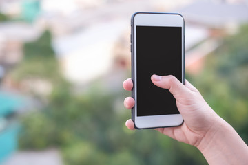hand holding smartphone or mobile phone with city building background and copy space.