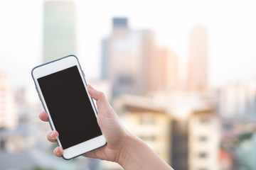 hand holding smartphone or mobile phone with city building background and copy space.